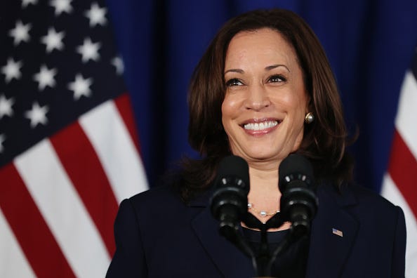 Picture of Vice President Kamala Harris at a podium in front of several American flags.