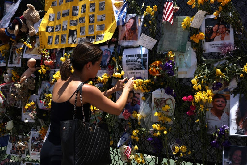 Mourners pay respects at the memorial site for victims of the Surfiside collapse.