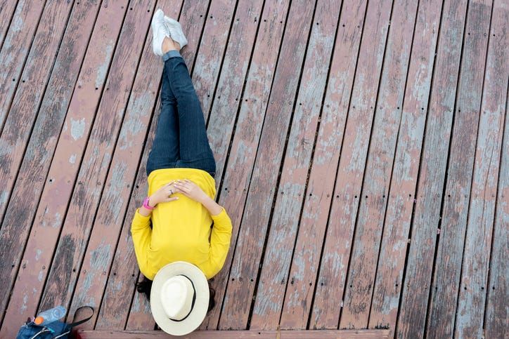 a woman relaxing on the deck with a hat over he head