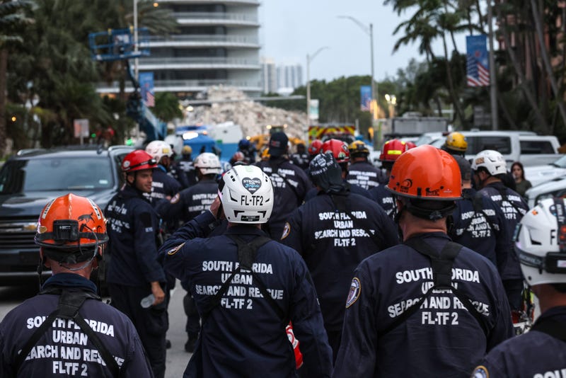 Search and rescue personnel walk back to work on the recovery operation at the collapsed 12-story Champlain Towers South