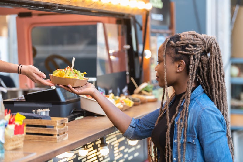 Afro american woman getting a delicious looking tray with nachos from a fast food truck. S