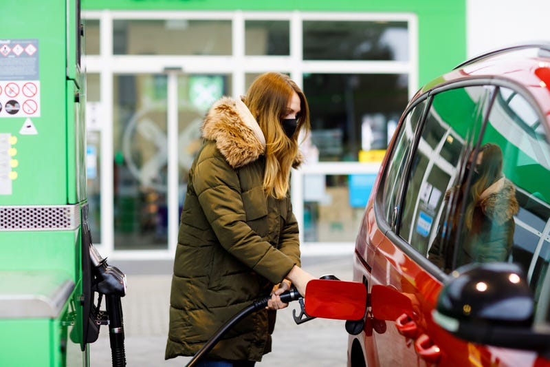 Woman wear medical mask at self-service gas station, hold fuel nozzle, refuel the ca