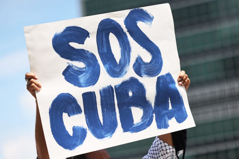 A person holds up a protest sign as people gather calling for help for Cuban protestors