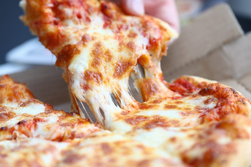 Someone pulling a piece of pizza onto their plate.