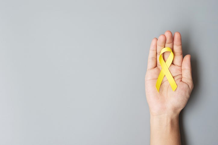 A hand holding a suicide prevention ribbon often worn in Suicide Prevention Month in September. 