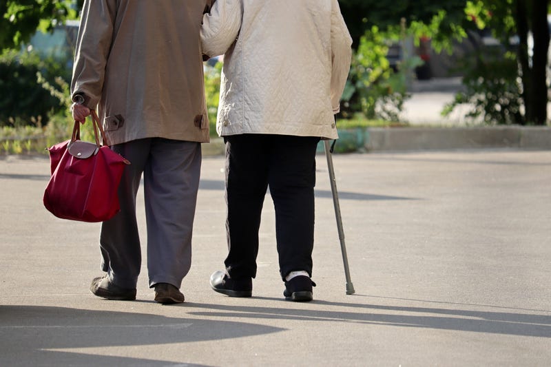 Two older people walking in the street together