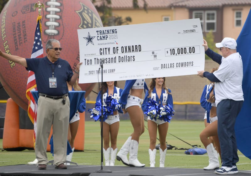 Owner Jerry Jones of the Dallas Cowboys presents a check for the city of Oxnard to the Mayor, John C. Zaragoza, for $10,000 as they welcome fans to training camp at River Ridge Complex on July 24, 2021 in Oxnard, California. 