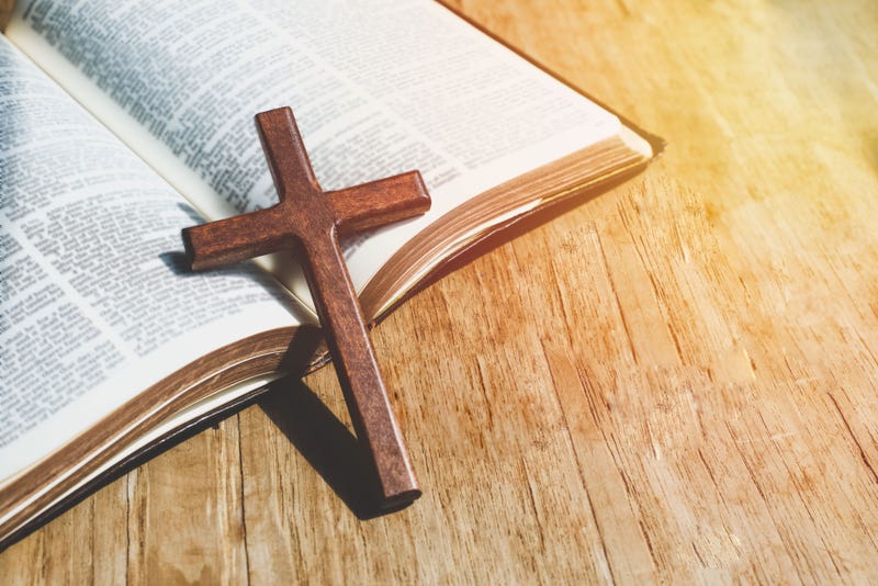 Closeup of simple wooden Christian cross necklace on Old Bible. Christian background with copy space