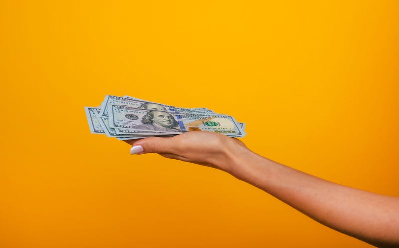 Close up photo of beautiful female hands holding the bunch of dollars of USA isolated on yellow background.