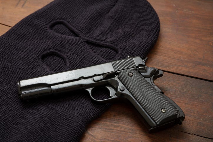 Black ski mask and handgun on a wooden table