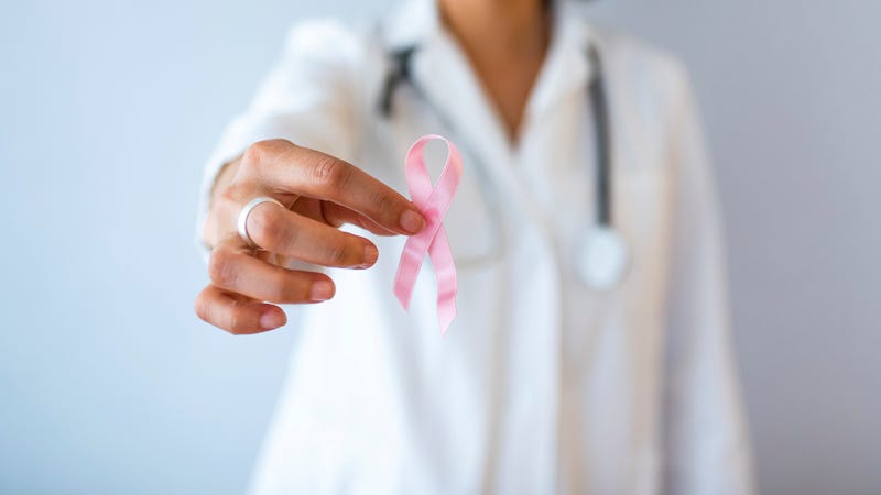 A doctor holding a breast cancer ribbon.