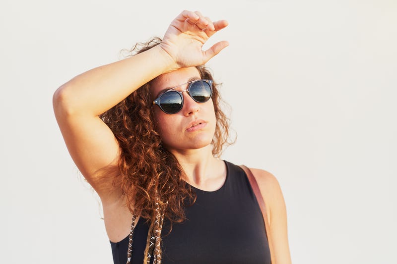 woman in sunglasses wiping sweat from brow