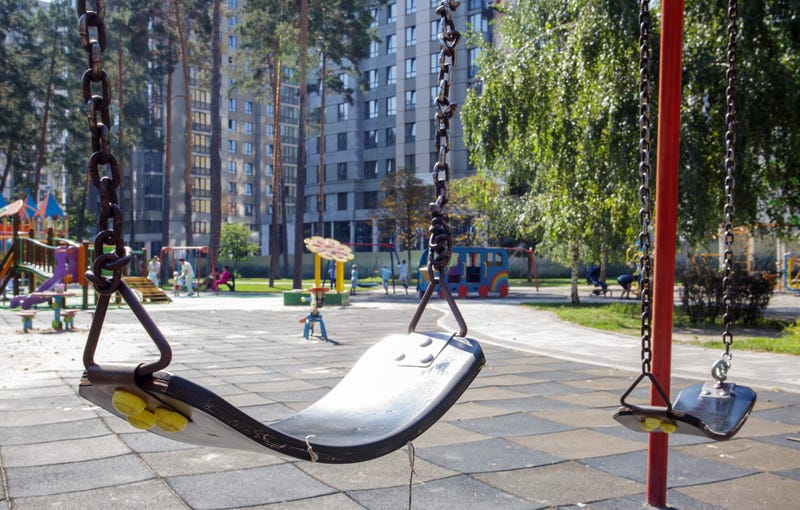 An empty seat on a swing set at a playground.
