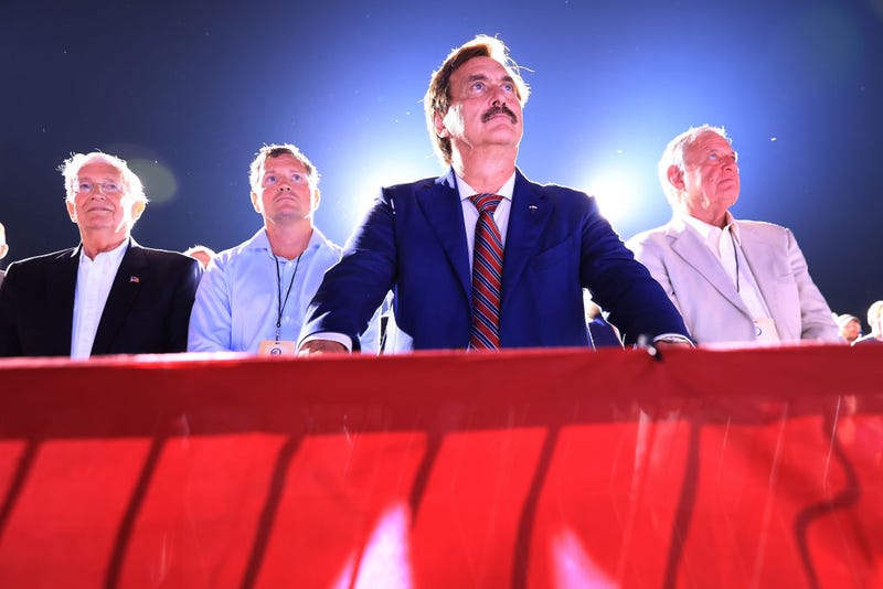 Founder and CEO of My Pillow, conservative political activist and conspiracy theorist Mike Lindell (C) listens to former U.S. President Donald Trump addresses supporters during a "Save America" rally at York Family Farms on August 21, 2021 in Cullman, Alabama.