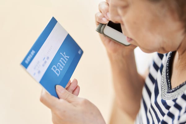 Elderly woman making a phone call while holding bank book