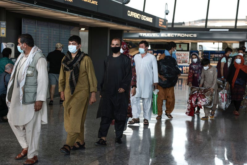 People evacuated from Afghanistan are led through the arrival terminal at the Dulles International Airport to board a bus that will take them to a refugee processing center on August 25, 2021 in Dulles, Virginia.