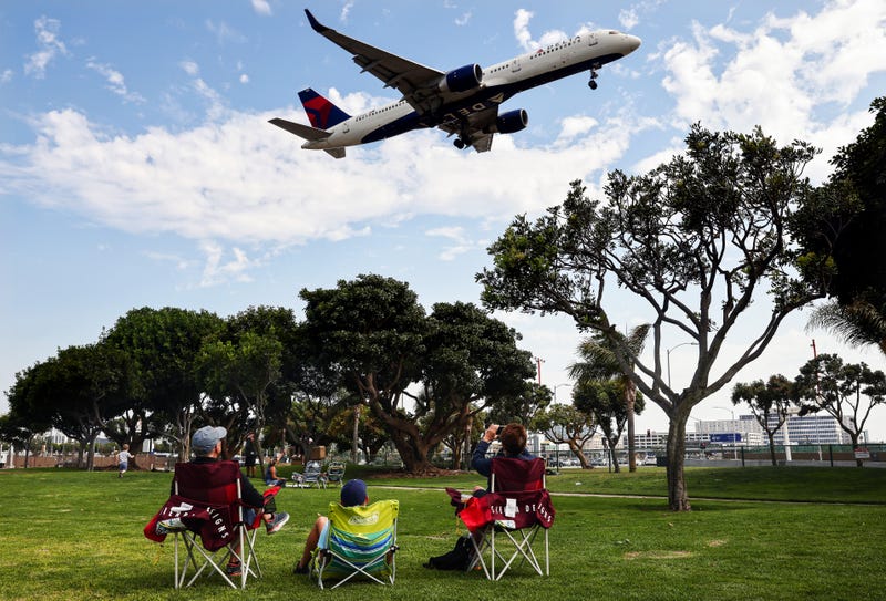People watch a Delta Air Lines plane land from a park next to Los Angeles International Airport (LAX) in 2021.