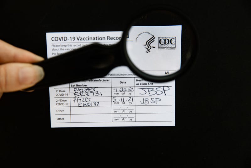 A photo of a hand using a magnifying glass to check the authenticity of a Covid-19 vaccine card, taken on Aug. 15, 2021 in Melville, NY.
