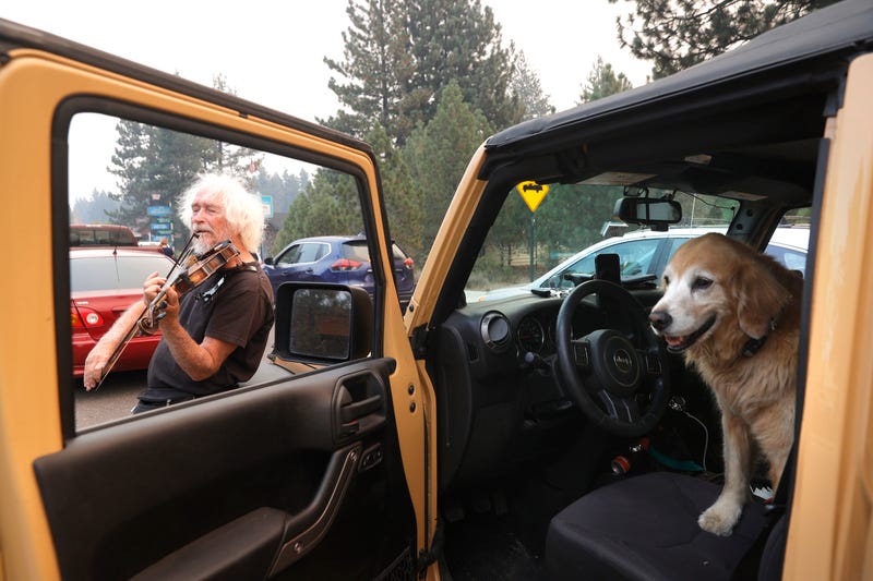 Evacuee Mel Smothers plays violin as he waits in a miles-long traffic jam on Highway 50 as people evacuate ahead of the Caldor Fire in South Lake Tahoe.