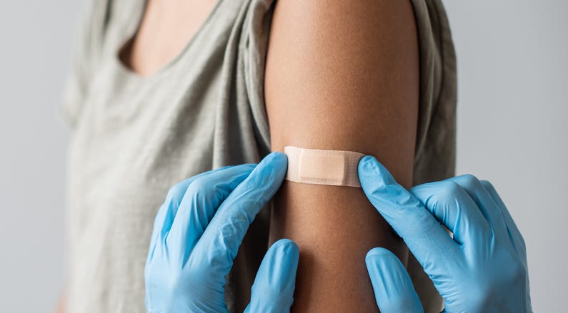Medical healthcare worker putting bandage on the female arm