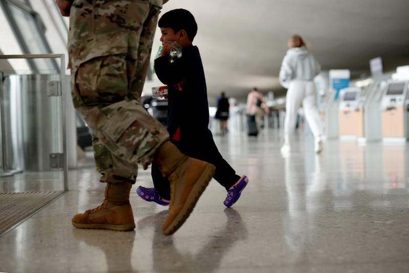 An Afghan boy walks with a U.S. service member as he and his family are led through the Dulles International Airport to board a bus that will take them to a refugee processing center after being evacuated from Kabul following the Taliban takeover of Afghanistan on August 31, 2021 in Dulles, Virginia.