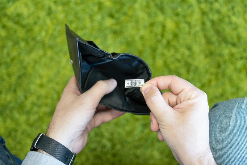 Person holding a dollar that is tiny in a wallet. 