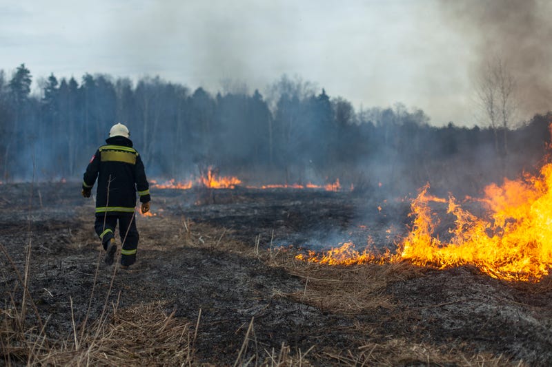 firefighter battling brush fire in open field