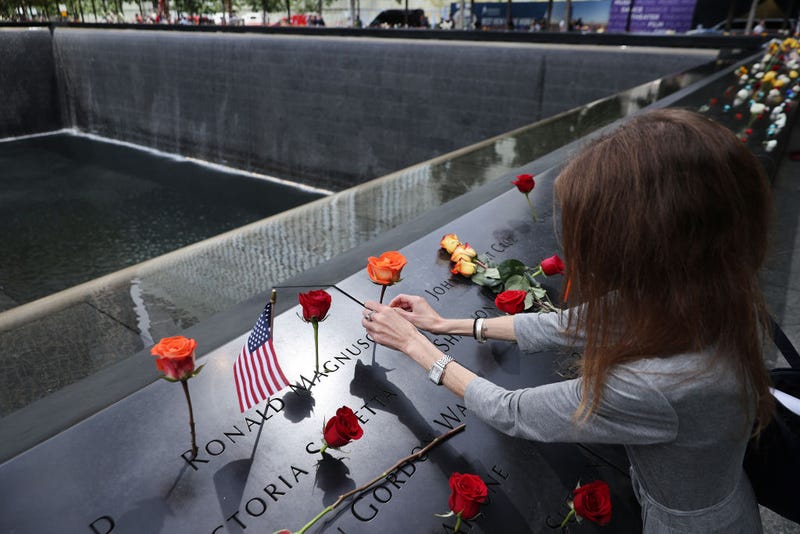 Sheryl Magnuson places a flower in her father's name where it is inscribed on the National 9/11 Memorial south pool following the commemoration ceremony at the memorial on September 11, 2021 in New York City. 