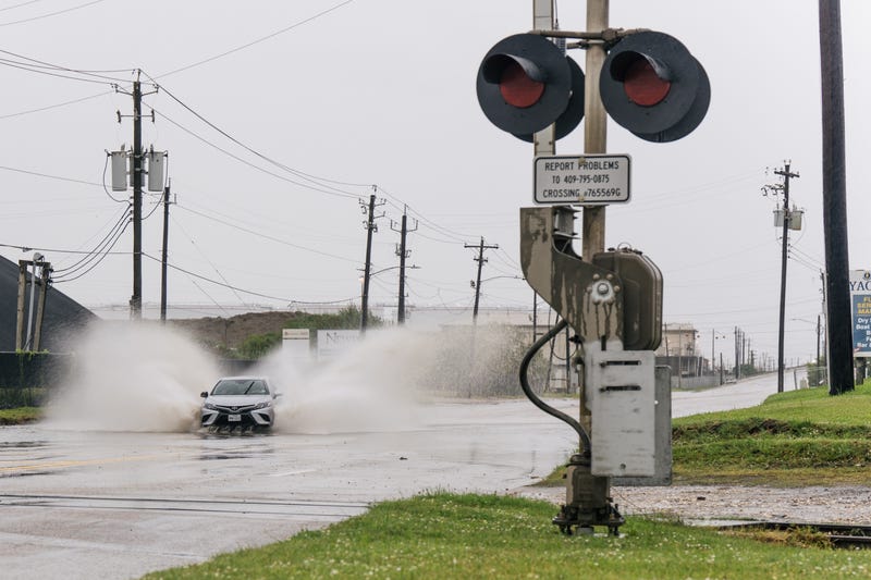 FILE: A car speeds through a flooded street ahead of the Tropical Storm Nicholas on September 13, 2021 in Galveston, Texas.