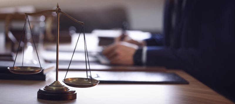 Scales of justice and a lawyer at a desk.