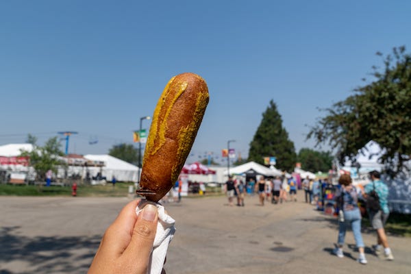 Corn dog smothered in mustard at a fair
