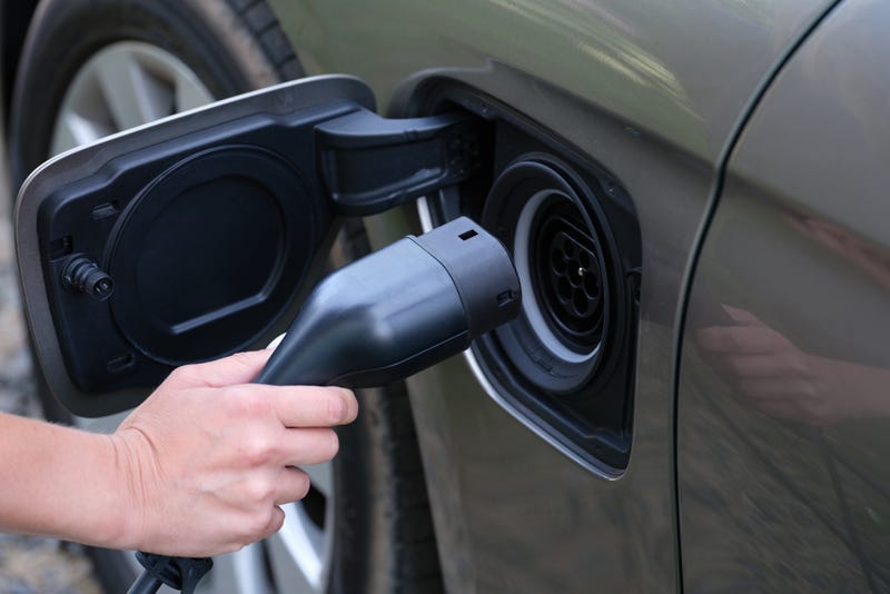 Man inserting electric cable into car charger closeup. Environmentally friendly cars concept