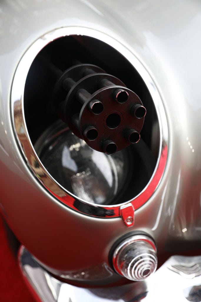 A machine gun poking of a headlight on James Bond's Aston Martin during the "NO TIME TO DIE" premiere.