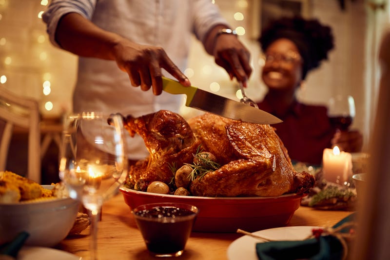 Person cutting into a Turkey on Thanksgiving. 