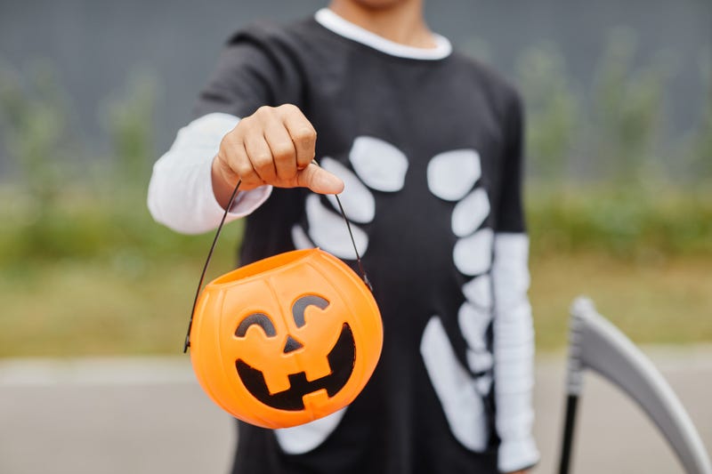 Kid in skeleton costume with jack-o-lantern