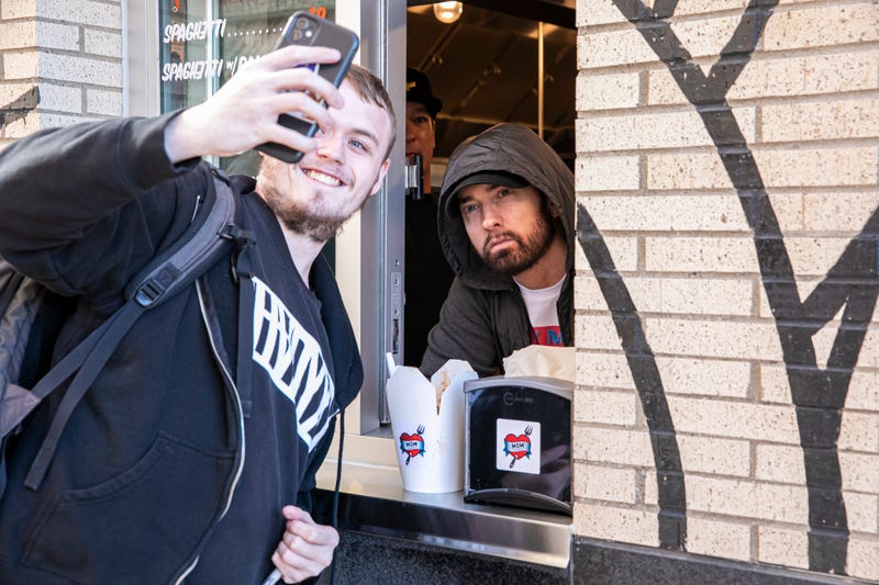 Eminem serves Mom's Spaghetti and takes a selfie with a fan on the opening night of his restaurant "Mom's Spaghetti" on September 29, 2021 in Detroit, Michigan.