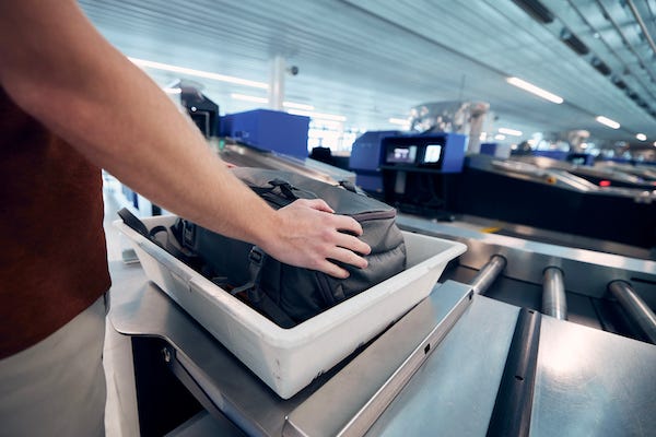 Man putting luggage through airport security check