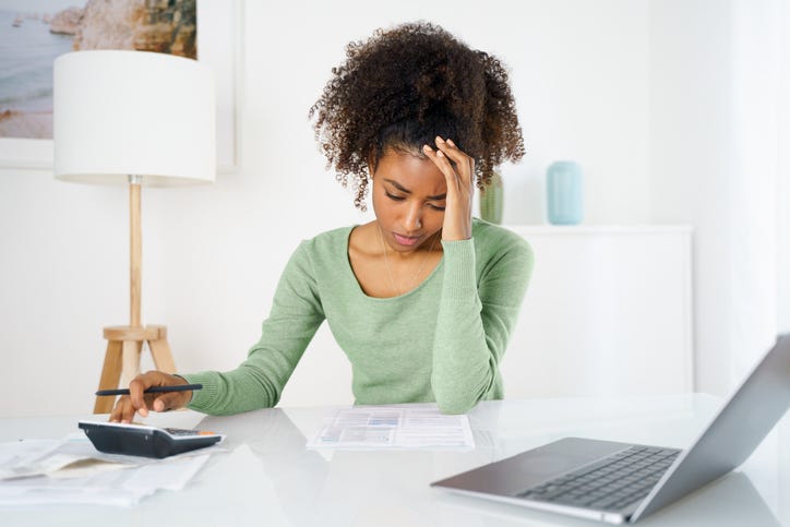 young woman stressed out while using as calculator and laptop