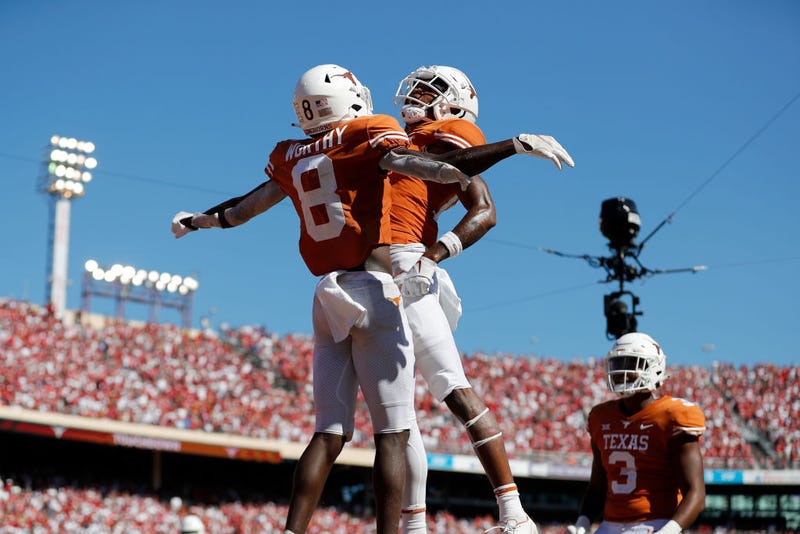 Xavier Worthy #8 of the Texas Longhorns celebrates with Marcus Washington #15 after a touchdown in the fourth quarter against the Oklahoma Sooners during the 2021 AT&T Red River Showdown at Cotton Bowl on October 09, 2021 in Dallas, Texas.