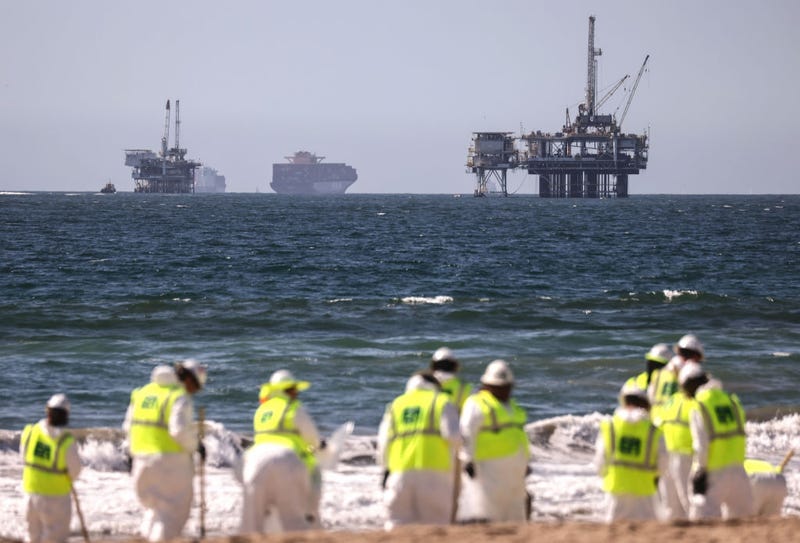 Cleanup workers search for contaminated sand and seaweed in front of drilling platforms and container ships about one week after an oil spill from an offshore oil platform on October 9, 2021 in Huntington Beach, California