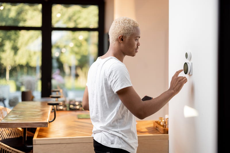 Man adjusts temperature on thermostat.