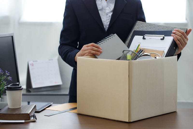 person at desk with box, packing up desk to leave