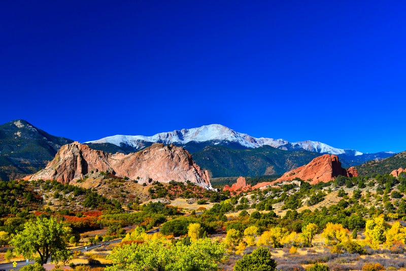 Snow capped Pikes Peak soaring over the Garden of the Gods Park in Colorado Springs, Colorado in a colorful Autumn morning.