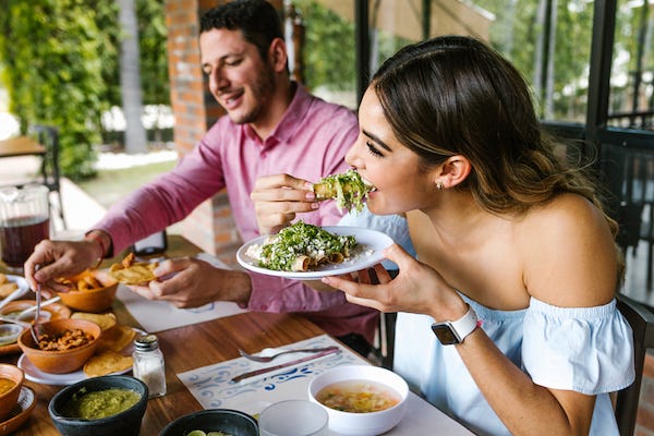 Woman eating tacos at a restaurant with friends