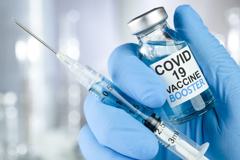 Hand in blue medical gloves holding a syringe and vaccine vial with COVID-19 vaccine booster