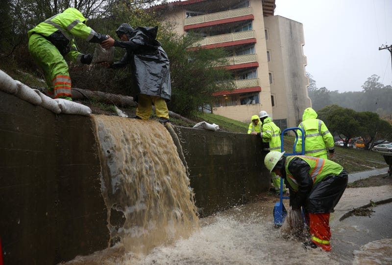 Workers try to divert water into drains as rain pours down on October 24, 2021 in Marin City, California.