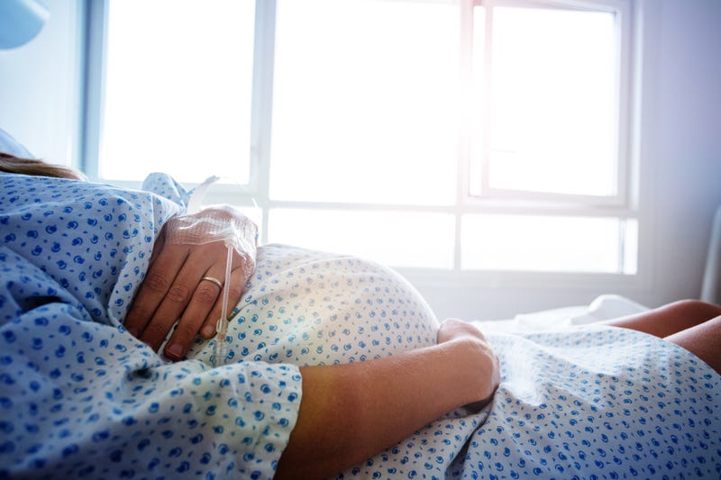 Close-up of a pregnant woman's belly in a hospital bed.