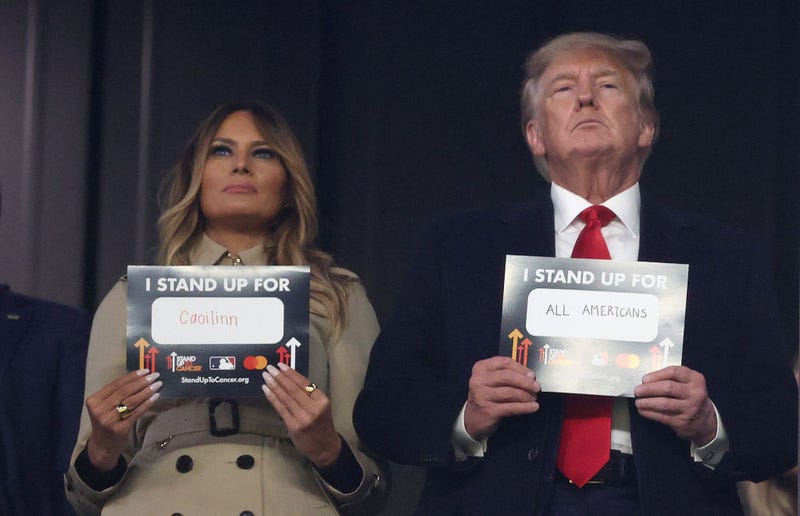 Former first lady and president of the United States Melania and Donald Trump hold up signs for "stand up to cancer" prior to the sixth inning in Game Four of the World Series between the Houston Astros and the Atlanta Braves Truist Park on October 30, 2021 in Atlanta, Georgia. (Photo by Elsa/Getty Images)