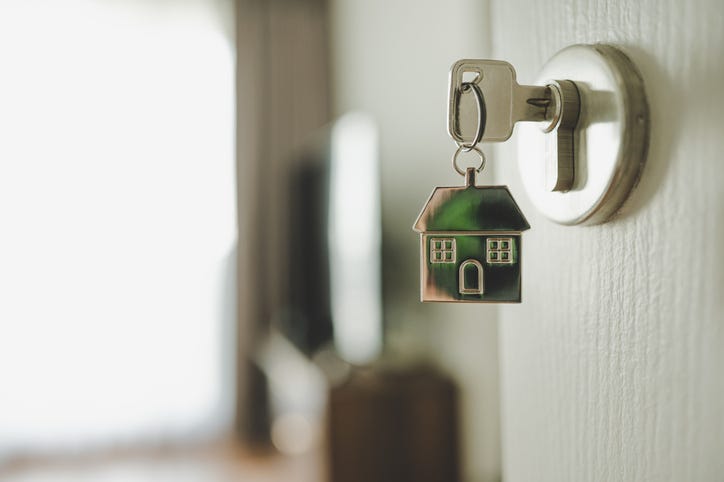 Key with a house keychain in a door. 