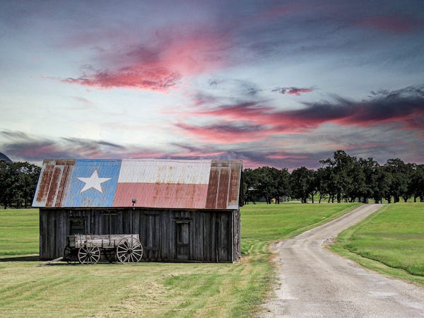 Texas flag on a barn roof at sunset